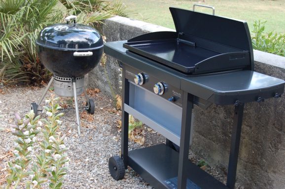 Barbecue au gaz et barbecue à charbon sur un patio en pierre.